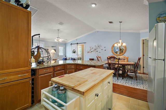 kitchen with wood counters, ornamental molding, vaulted ceiling, and freestanding refrigerator