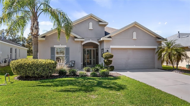 traditional-style home featuring a garage, driveway, a front yard, and stucco siding