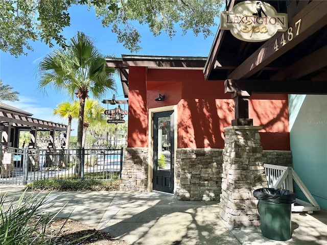 26747 White Plains Way, Leesburg, FL 34748 - property entrance featuring fence, stucco siding, a pergola, and stone siding