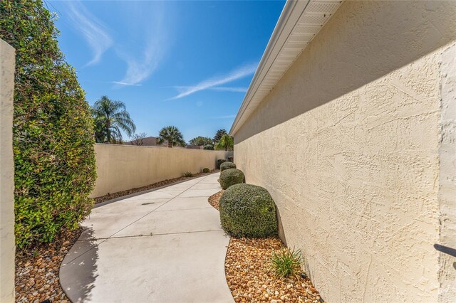 1202 San Bernardo Rd, The Villages, FL 32162 - view of side of home with a patio area, a fenced backyard, and stucco siding