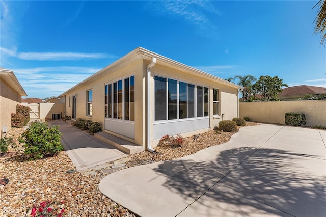 1202 San Bernardo Rd, The Villages, FL 32162 - view of side of home with a sunroom, a patio, fence, and stucco siding