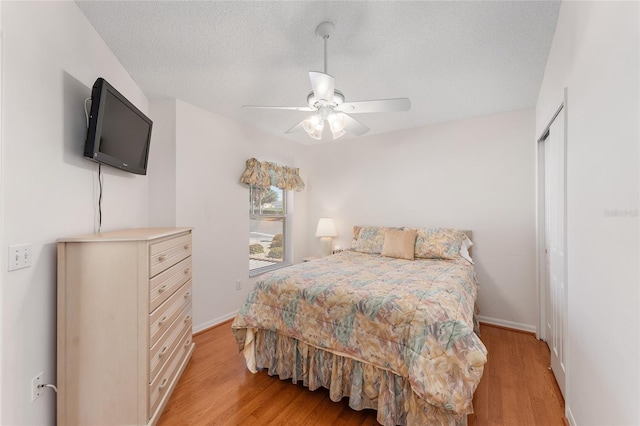 1202 San Bernardo Rd, The Villages, FL 32162 - bedroom featuring a textured ceiling, ceiling fan, light wood finished floors, and baseboards