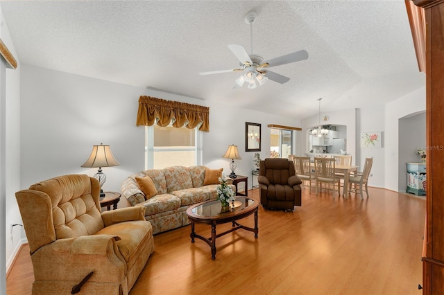 1202 San Bernardo Rd, The Villages, FL 32162 - living area featuring arched walkways, light wood-style floors, vaulted ceiling, a textured ceiling, and ceiling fan with notable chandelier