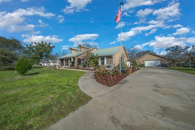 view of front of house with metal roof, a detached garage, and a front lawn