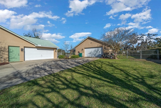 exterior space with metal roof, a garage, fence, a lawn, and stucco siding