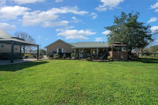 rear view of property featuring a yard, a patio area, metal roof, and a gazebo