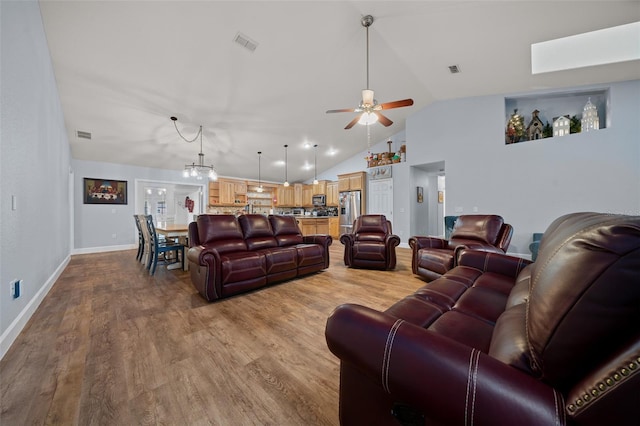 living area with baseboards, visible vents, wood finished floors, high vaulted ceiling, and ceiling fan with notable chandelier