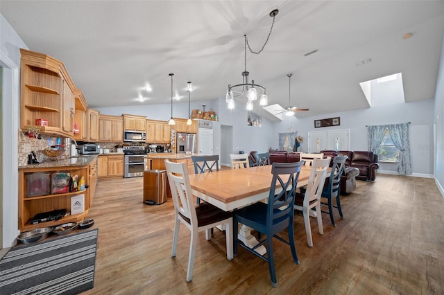 dining area featuring visible vents, light wood-style floors, vaulted ceiling, ceiling fan, and baseboards