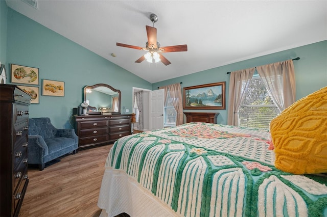 bedroom with ceiling fan, visible vents, vaulted ceiling, and wood finished floors