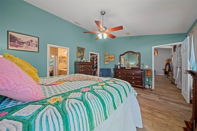 bedroom featuring visible vents, ceiling fan, wood finished floors, a spacious closet, and vaulted ceiling