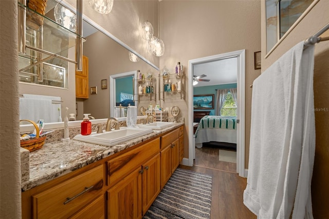 bathroom with double vanity, connected bathroom, a sink, and wood finished floors