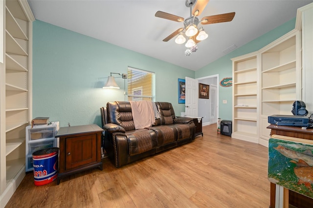 living room with built in features, a ceiling fan, vaulted ceiling, and wood finished floors