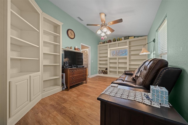 living room with lofted ceiling, wood finished floors, visible vents, baseboards, and a ceiling fan