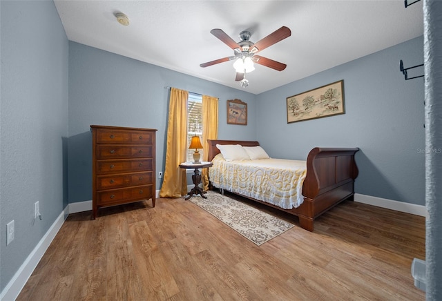 bedroom with ceiling fan, baseboards, and wood finished floors