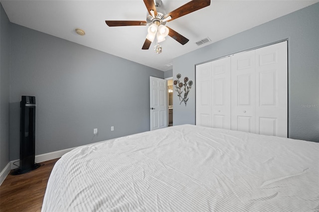 bedroom featuring ceiling fan, dark wood-type flooring, visible vents, baseboards, and a closet