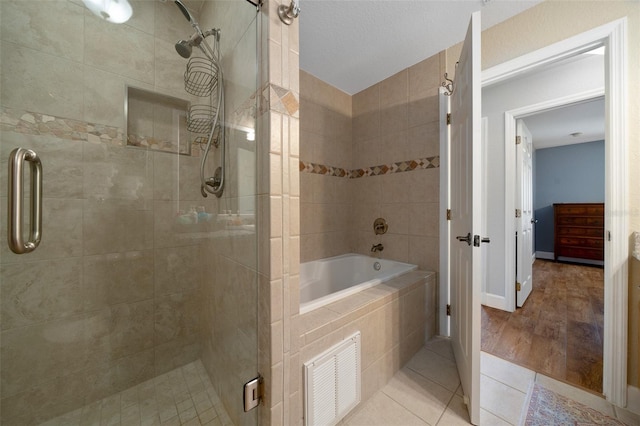 full bath featuring a relaxing tiled tub, visible vents, a stall shower, baseboards, and tile patterned floors