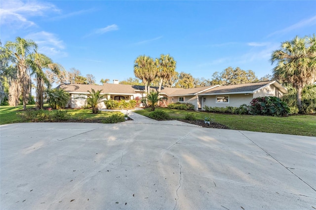 single story home with concrete driveway and a front lawn