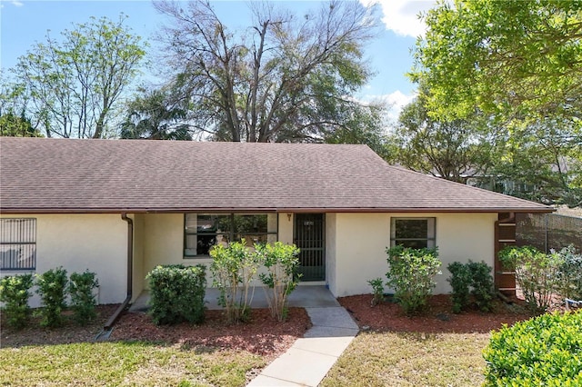 single story home featuring roof with shingles and stucco siding