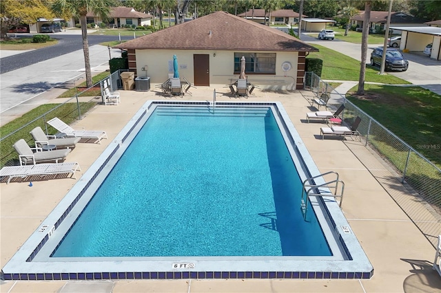 pool with a patio, central AC unit, and fence