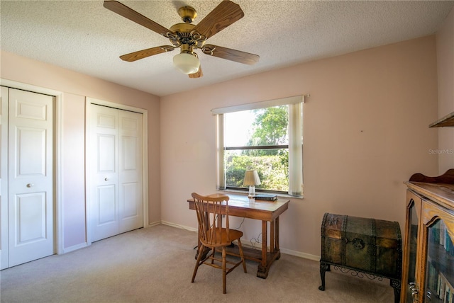 office space with light carpet, a textured ceiling, and baseboards