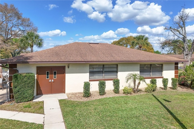 ranch-style home featuring a front lawn, a shingled roof, and stucco siding