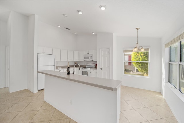 kitchen with light tile patterned floors, light countertops, white appliances, and white cabinetry