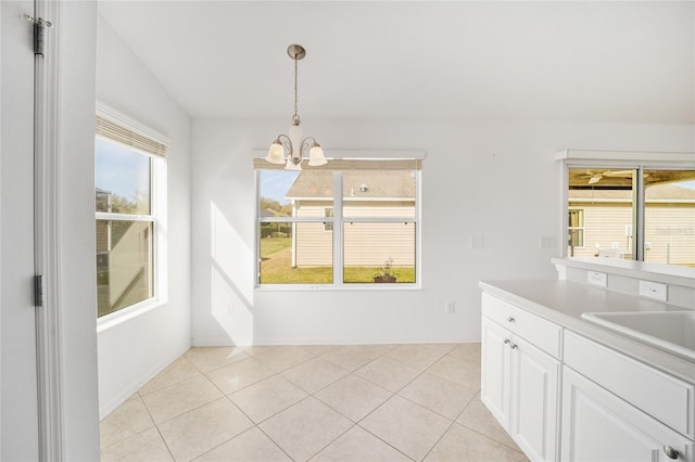 unfurnished dining area featuring an inviting chandelier, light tile patterned floors, and a sink