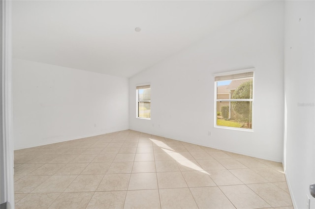 empty room featuring lofted ceiling and light tile patterned flooring