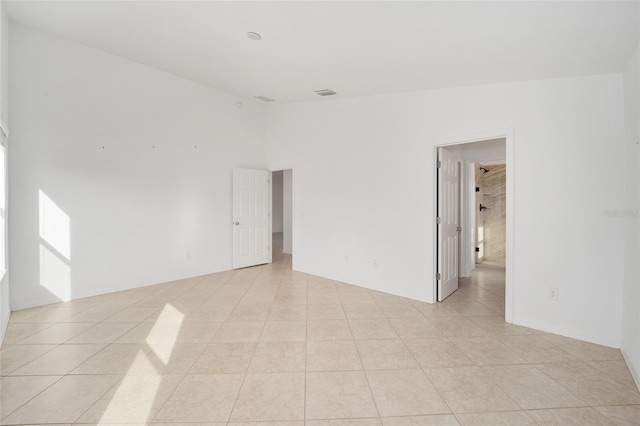 empty room with lofted ceiling, visible vents, and light tile patterned flooring