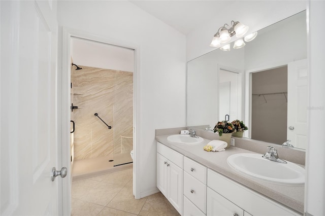 bathroom featuring double vanity, a stall shower, a sink, and tile patterned floors