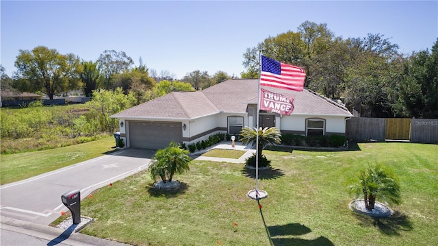 view of front of home with an attached garage, driveway, fence, and a front yard