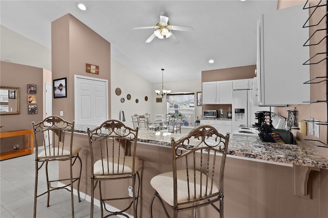 kitchen with a peninsula, stone counters, white cabinetry, and a kitchen breakfast bar