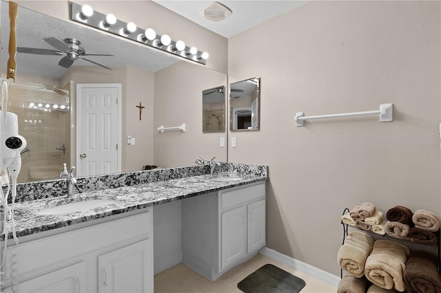 bathroom with ceiling fan, a sink, a tile shower, and double vanity