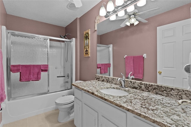 bathroom featuring toilet, ceiling fan, tile patterned floors, combined bath / shower with glass door, and vanity