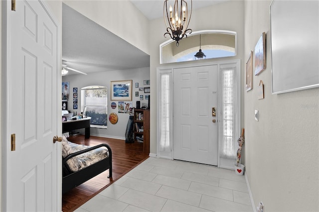 entryway featuring an inviting chandelier, light tile patterned floors, and baseboards