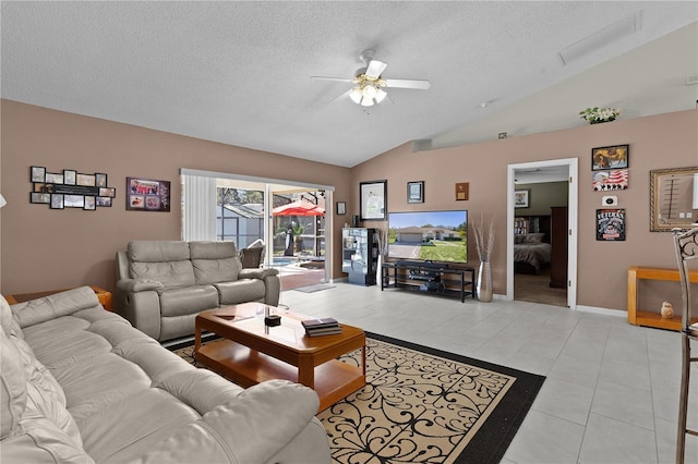 living room with light tile patterned floors, baseboards, ceiling fan, vaulted ceiling, and a textured ceiling