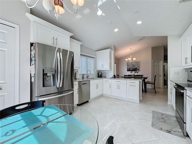 kitchen with light tile patterned floors, a notable chandelier, stainless steel appliances, a peninsula, and backsplash