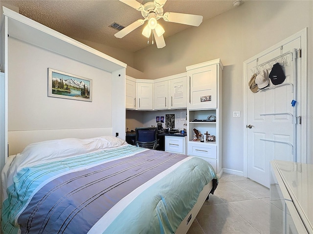 bedroom featuring built in desk, visible vents, light tile patterned flooring, ceiling fan, and a textured ceiling