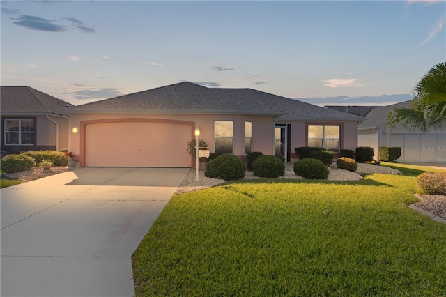 single story home featuring a garage, driveway, a front yard, and stucco siding