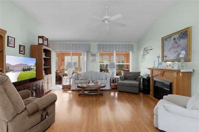 living room with light wood-style floors, vaulted ceiling, a fireplace, and ceiling fan