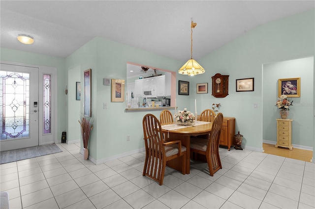 dining area with light tile patterned floors, lofted ceiling, and baseboards