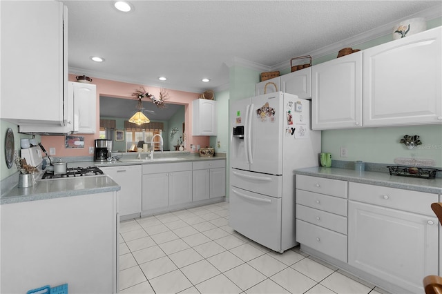 kitchen with white appliances, crown molding, white cabinets, and a sink