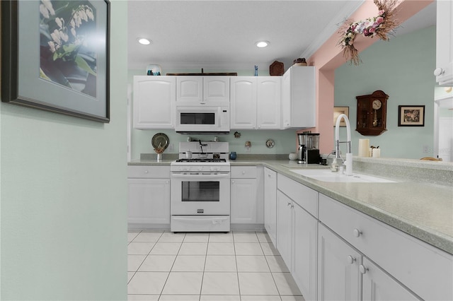 kitchen featuring light tile patterned floors, light countertops, white cabinets, a sink, and white appliances