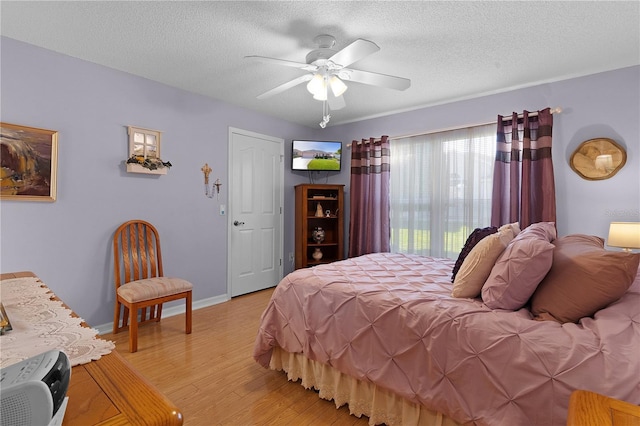 bedroom with baseboards, ceiling fan, light wood-style flooring, and a textured ceiling