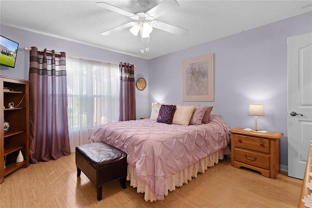 bedroom featuring a ceiling fan, light wood-style flooring, and a textured ceiling