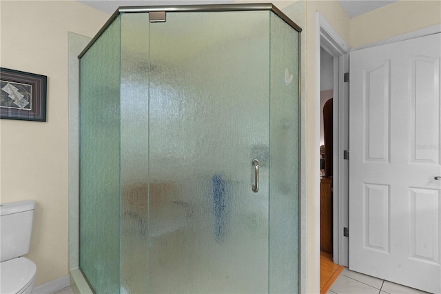 full bathroom featuring a shower stall, toilet, and tile patterned floors