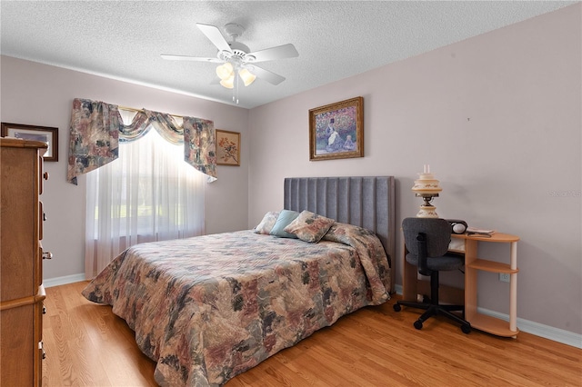 bedroom featuring a textured ceiling, ceiling fan, baseboards, and light wood-style floors