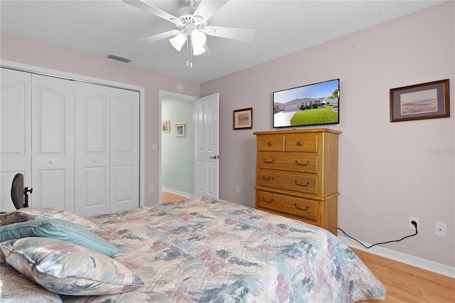 bedroom featuring a closet, visible vents, a textured ceiling, and light wood finished floors