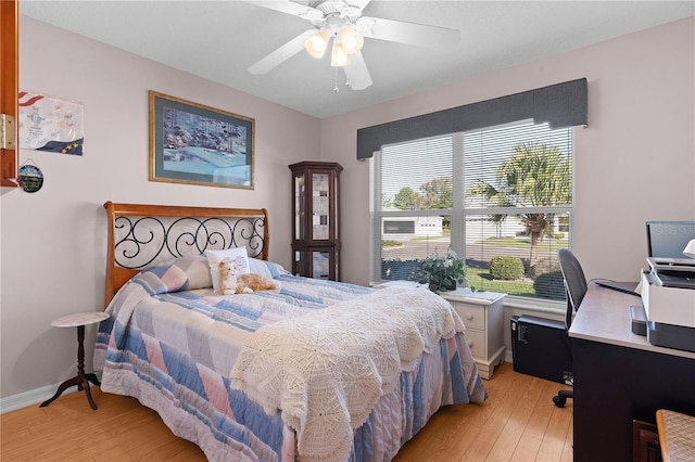 bedroom with light wood-style flooring, baseboards, and a ceiling fan