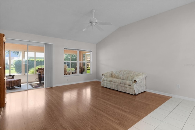 living area featuring wood finished floors, baseboards, ceiling fan, and lofted ceiling